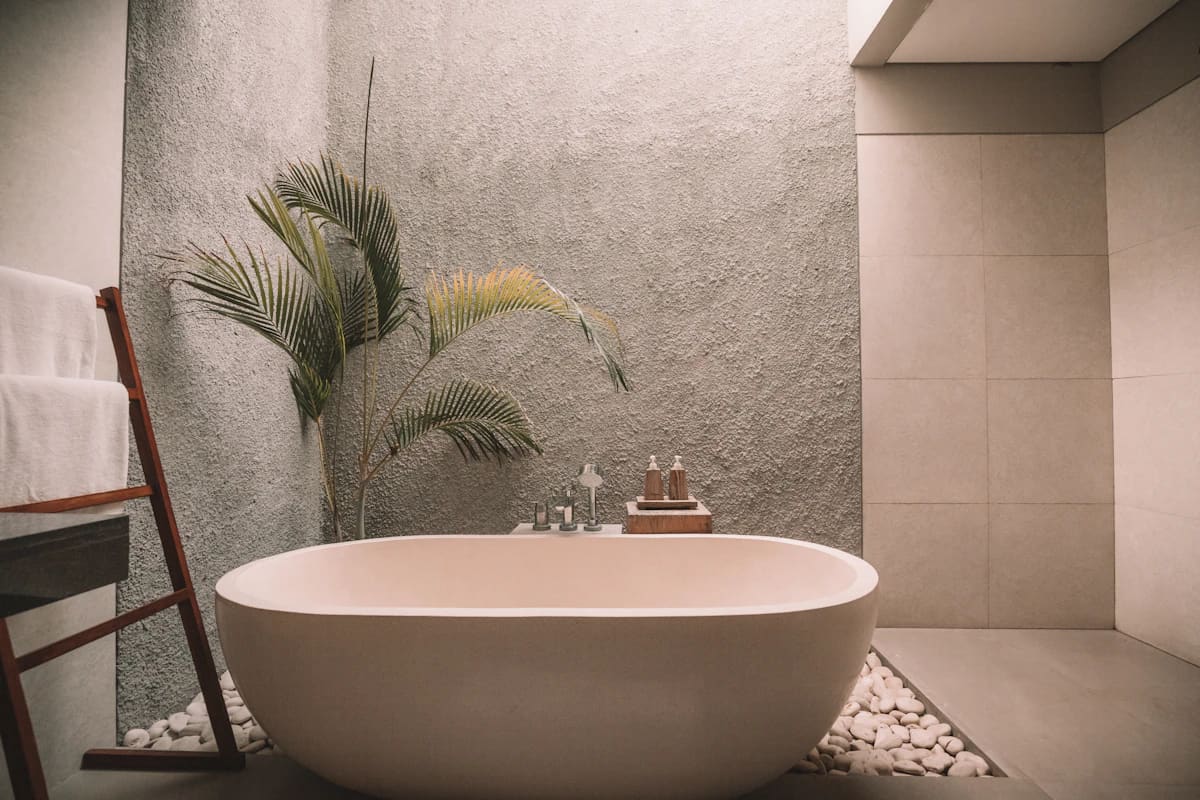 White freestanding oval bath against a stone wall