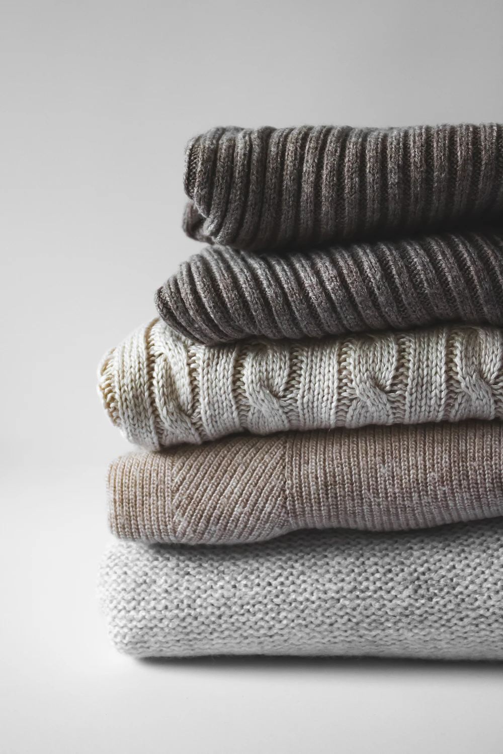A neat stack of folded knitwear in soft neutrals